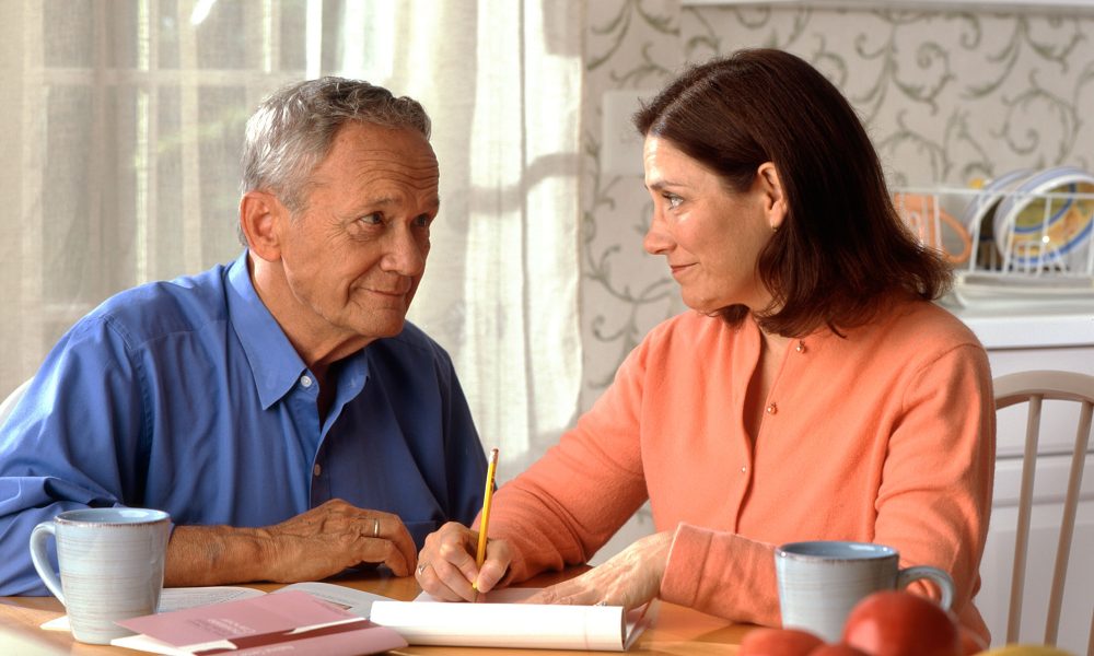 Senior couple reviewing household finances together at a kitchen table