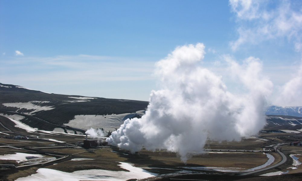 Steam rising from a geothermal power plant in a volcanic landscape