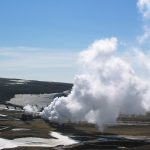 Steam rising from a geothermal power plant in a volcanic landscape