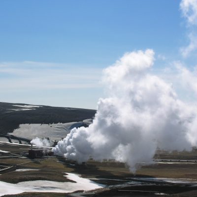 Steam rising from a geothermal power plant in a volcanic landscape